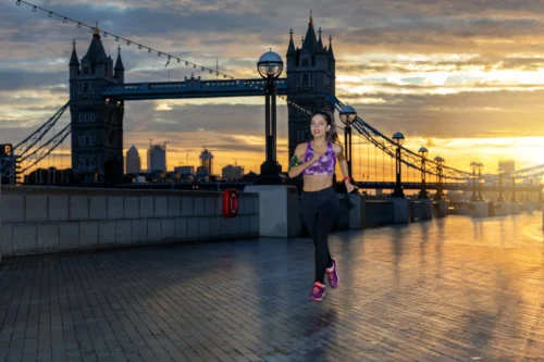 athletic woman jogging along Tower Bridge in London at sunrise