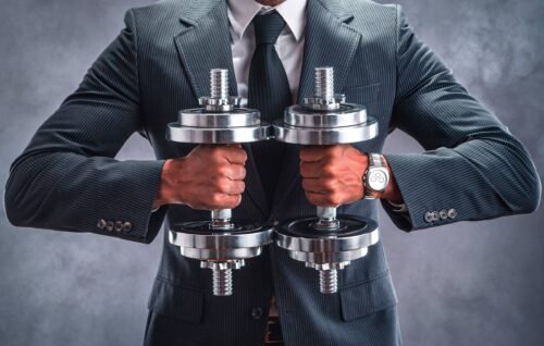 Man in a suit and tie holding dumbbells