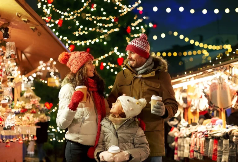 mother, father and little daughter with takeaway drinks at christmas market
