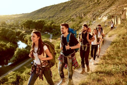 Group of happy backpackers trekking on sunny day