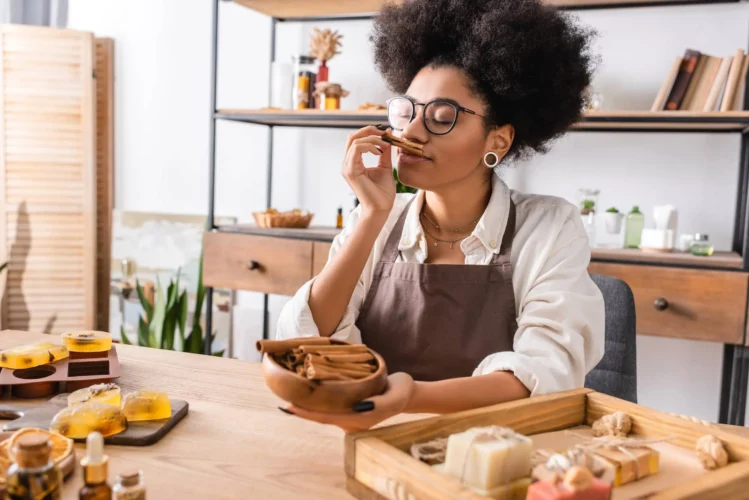 Craftswoman in eyeglasses enjoying flavor of cinnamon