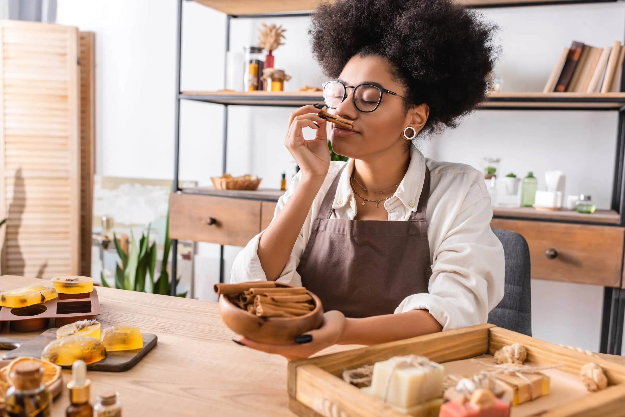 Craftswoman in eyeglasses enjoying flavor of cinnamon