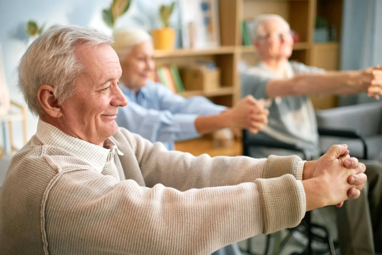 Elderly people in retirement home performing stretching exercises while seated