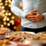 Person holds their stomach in pain against the background of a festive table with a lot of food