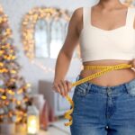 Person measuring waist with tape in room decorated for Christmas