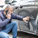 Man on phone after someone backed into the side door of his car