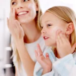 Skincare, mother and daughter home spa day washing their face in bathroom