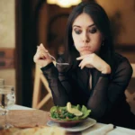 Unhappy Woman Eating a Salad by Herself in a Restaurant