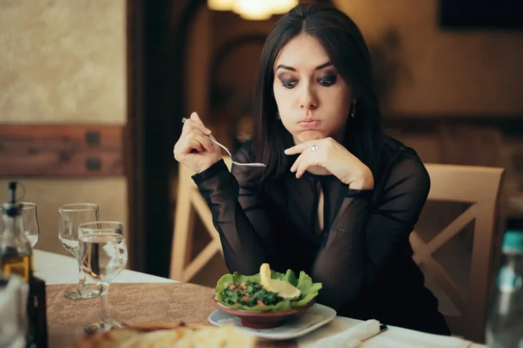 Unhappy Woman Eating a Salad by Herself in a Restaurant