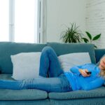 Bored woman watching TV at home changing channels with remote control