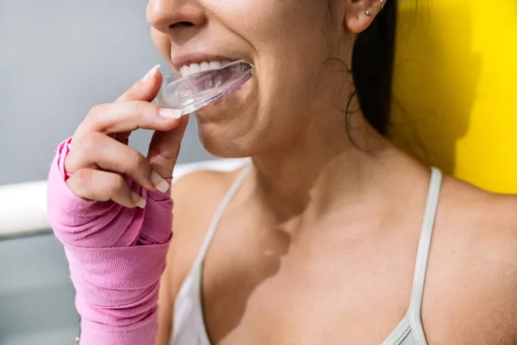 Female athlete putting on a mouth guard