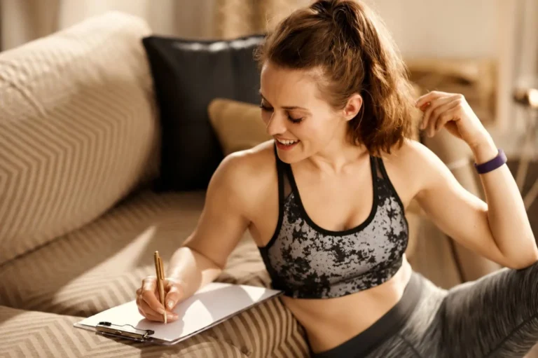Happy fit woman with clipboard and pen writing fitness goals