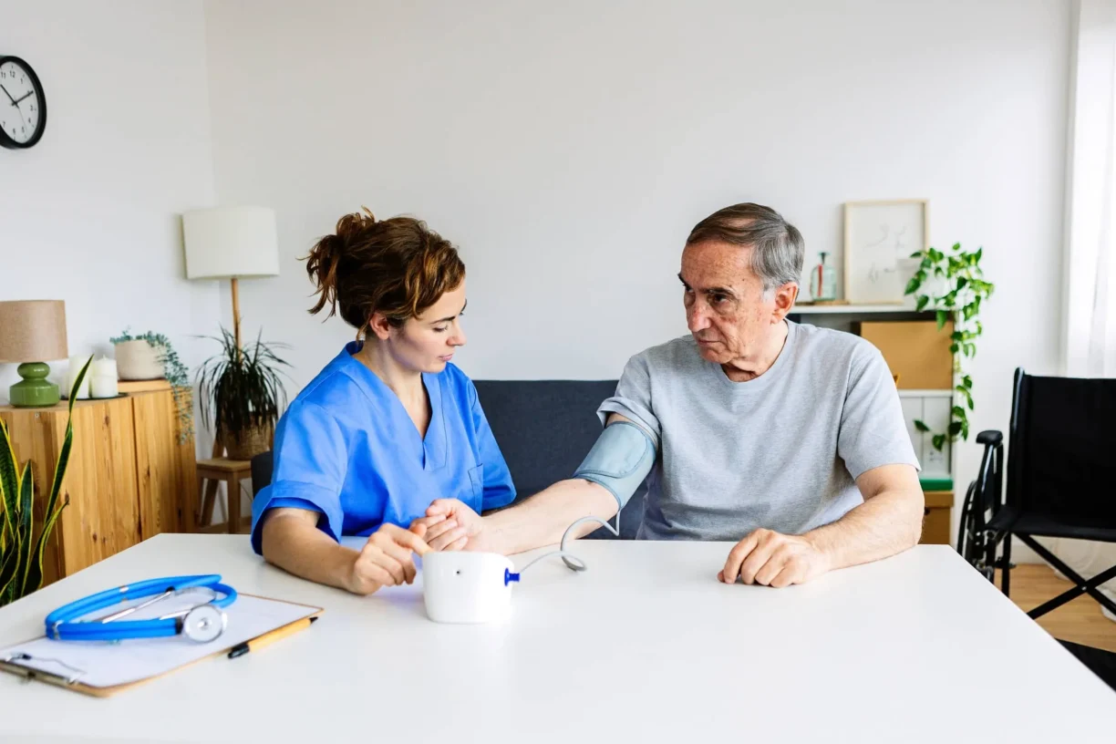 Nurse measuring blood pressure of man at home