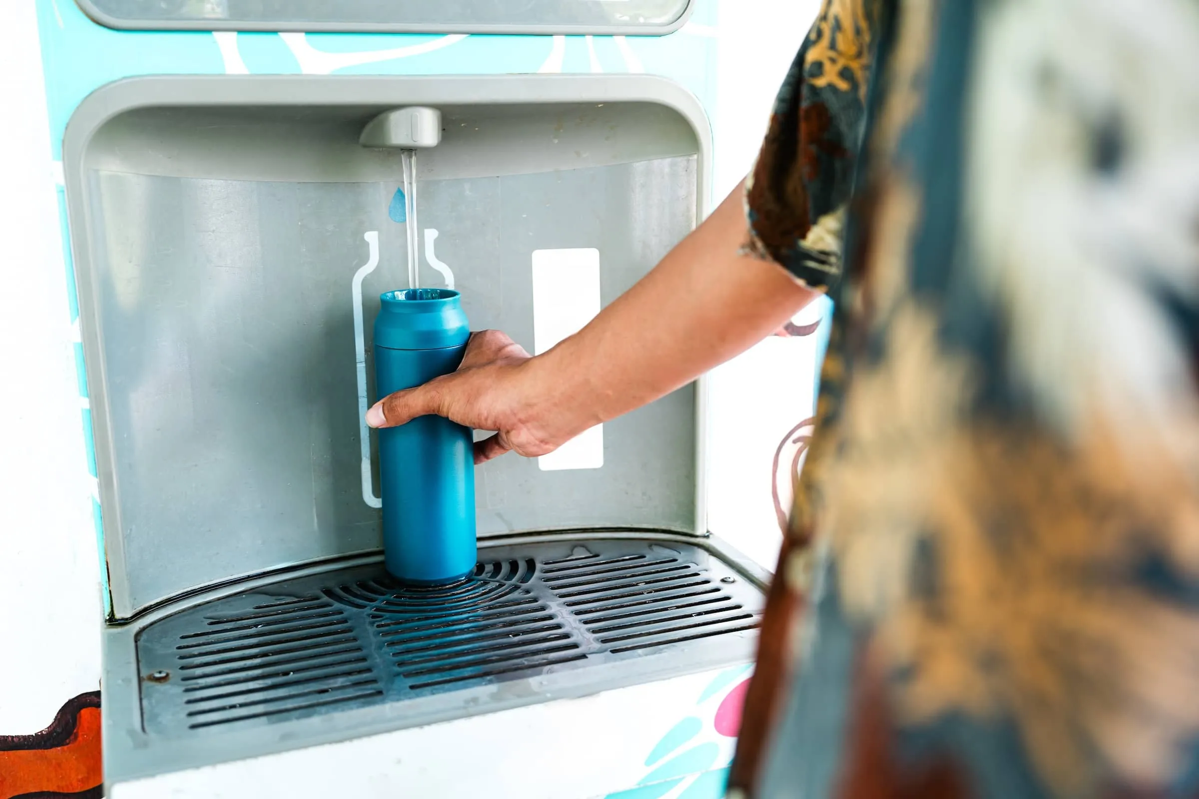 Refillable water bottle being filled at eco-friendly hydration station