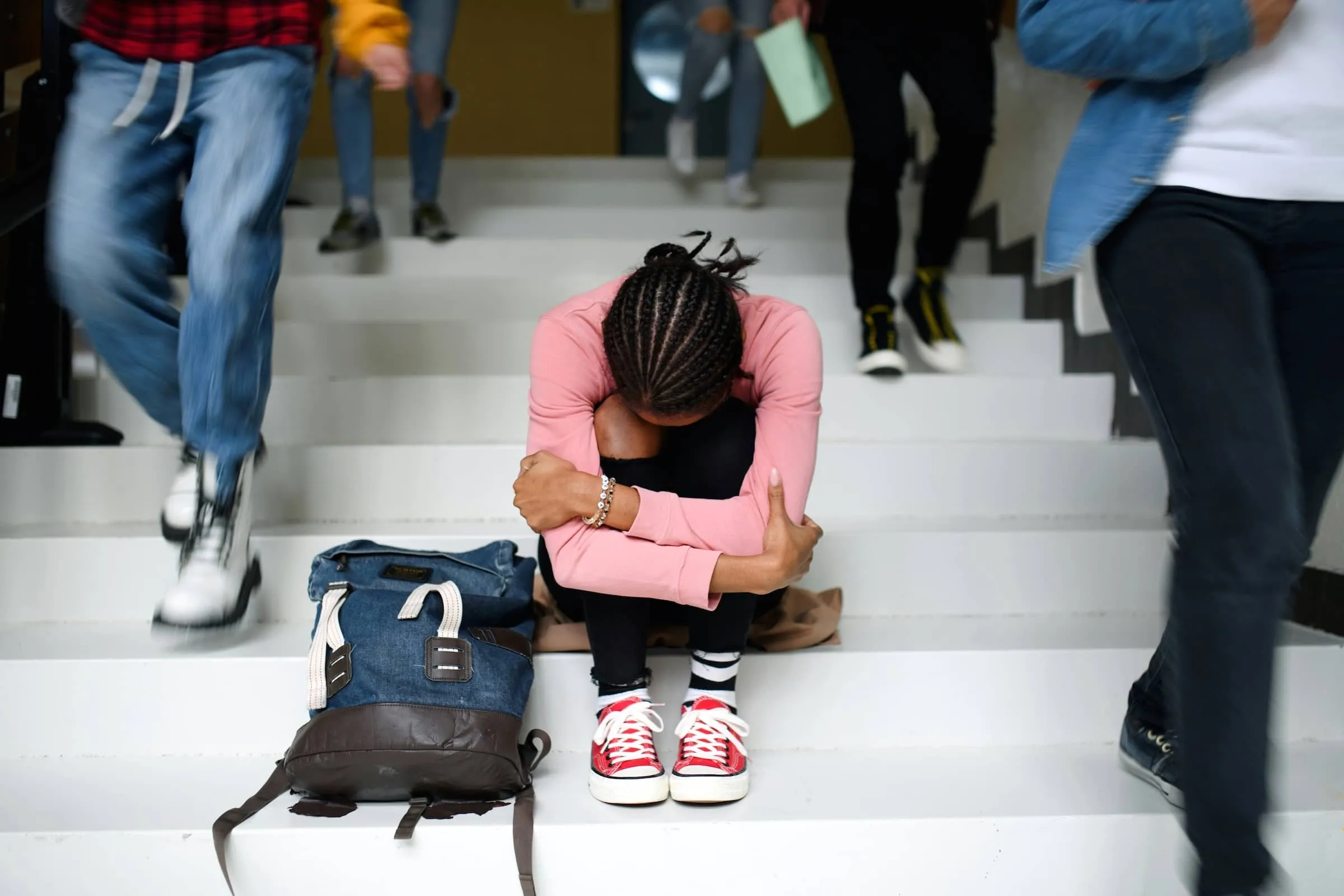 Young Person Sits on Stairs with Head Down