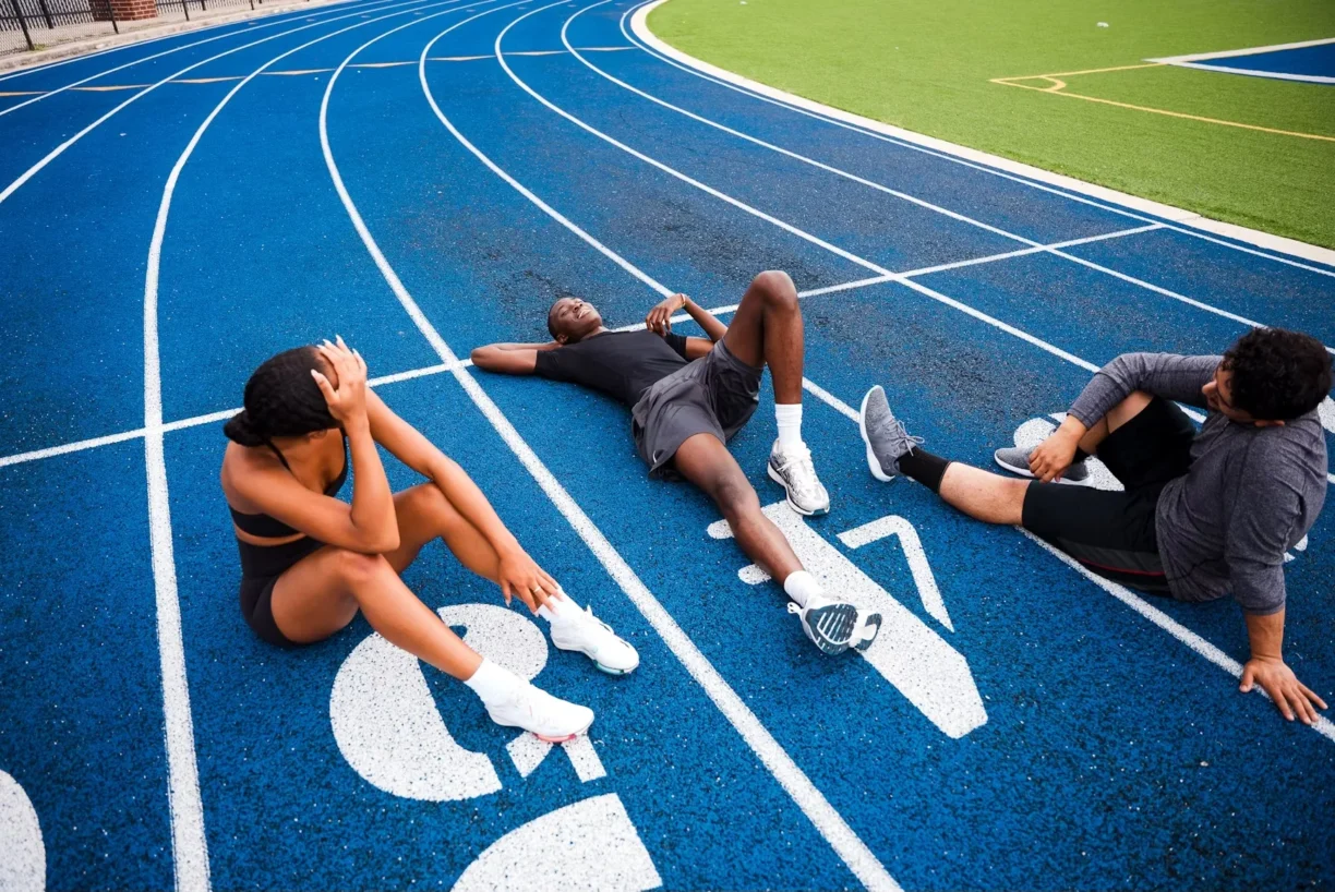 Athletes lay on the floor of running track