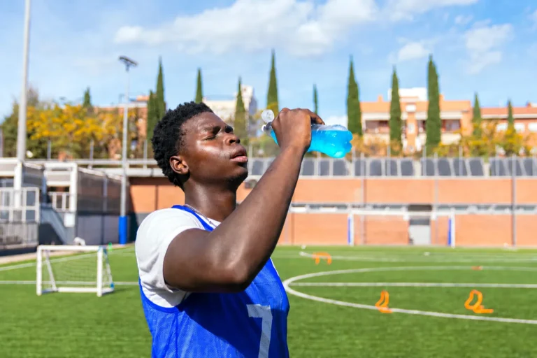 Young athlete drinks a sports drink on training pitch