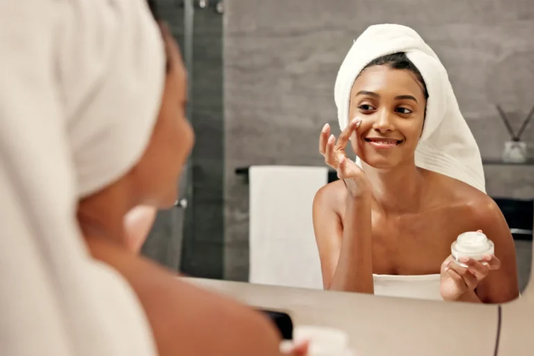 Person applies skin cream to face in mirror