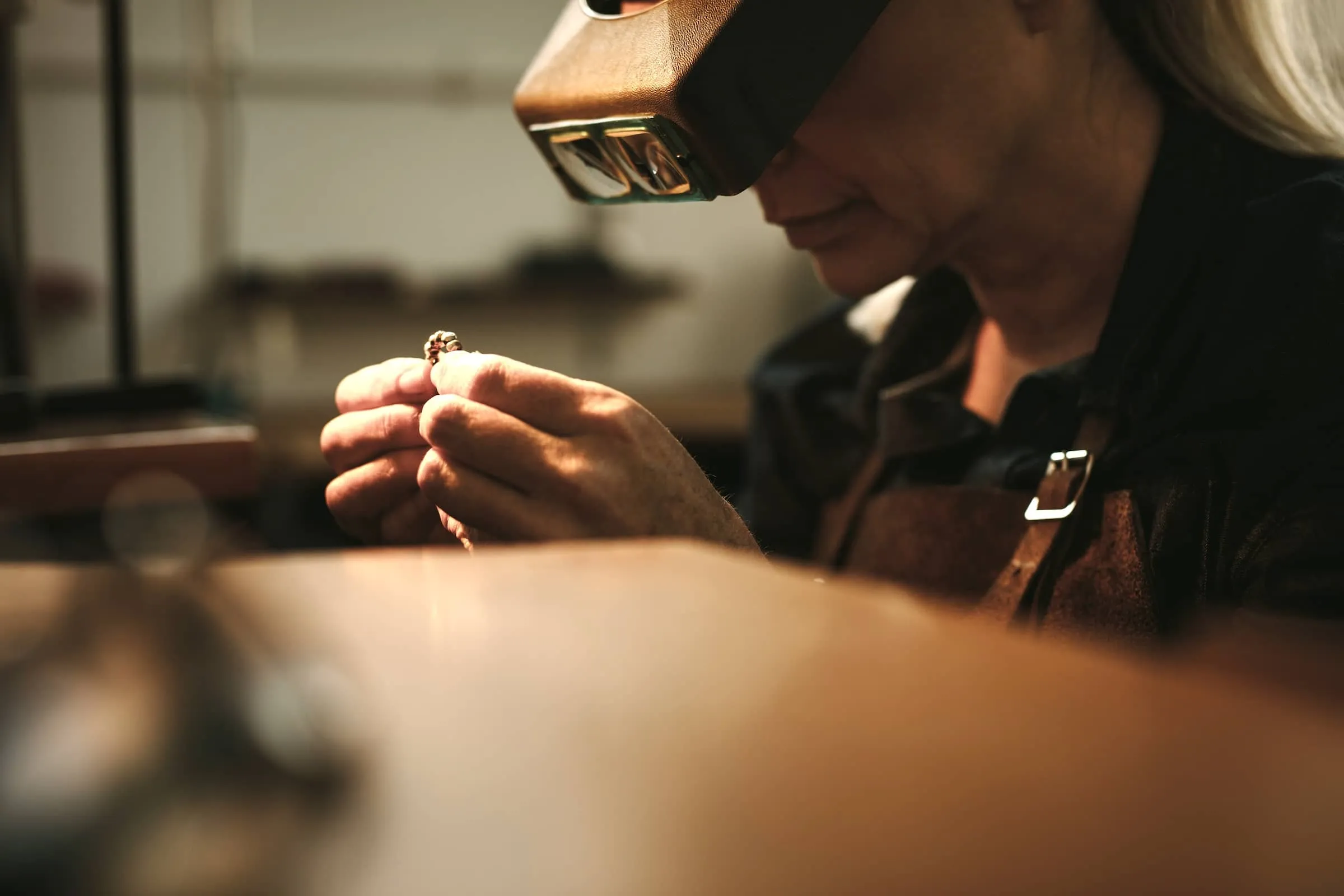 Female jeweler examining a ring through magnifier to check the quality