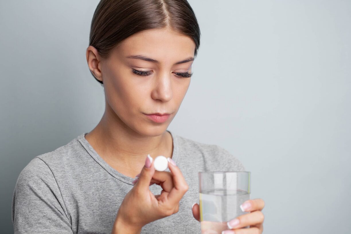 Woman taking pill with water