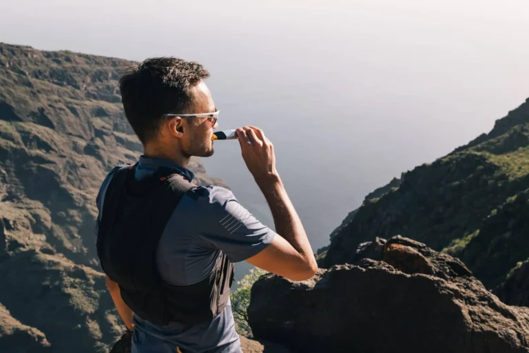 Sports Man with Gel in Mouth Overlooks Mountains