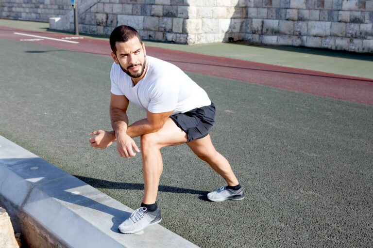 Sporty man stretching calf and leaning on knee