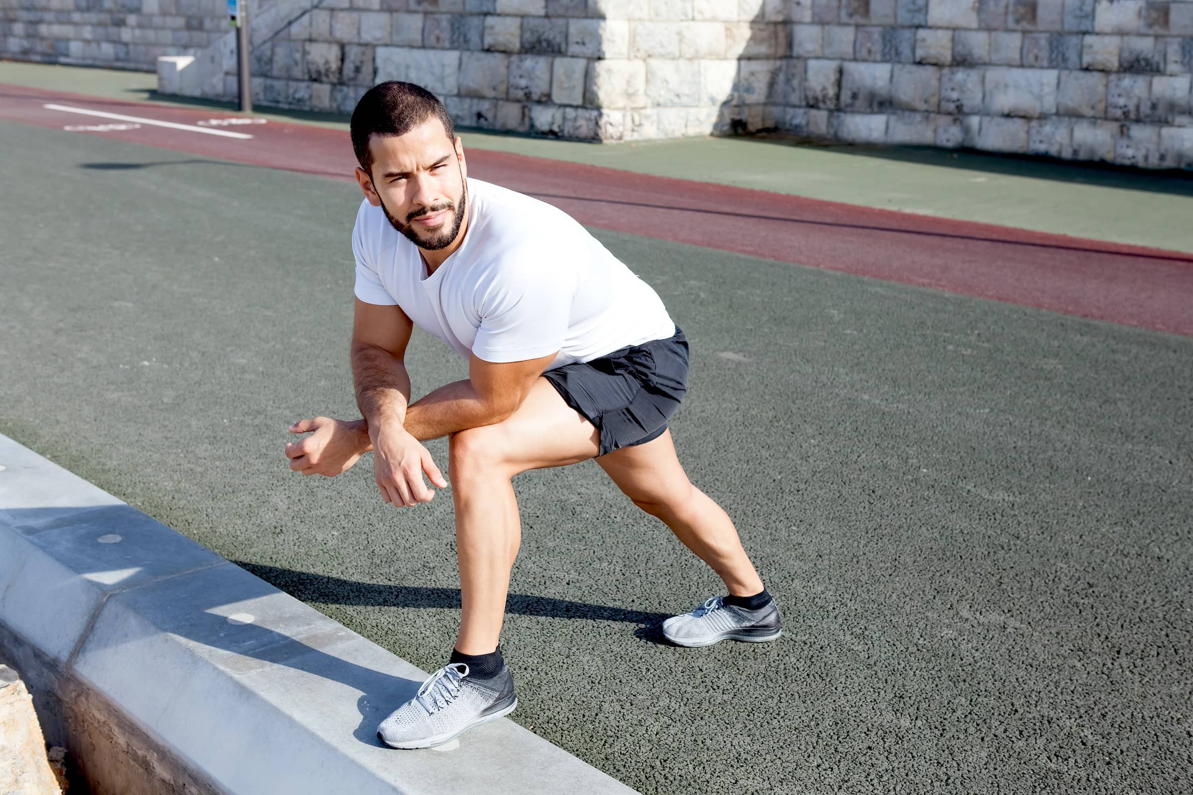 Sporty man stretching calf and leaning on knee