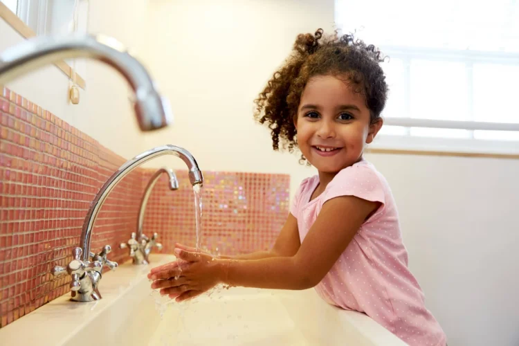 Female Pupil At School Washing Hands In Washroom