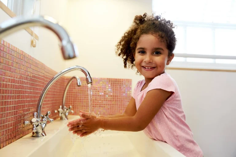 Female Pupil At School Washing Hands In Washroom