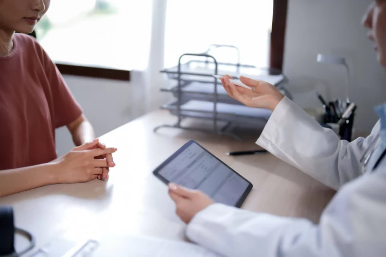 Person reading health examination results and writing notes on tablet