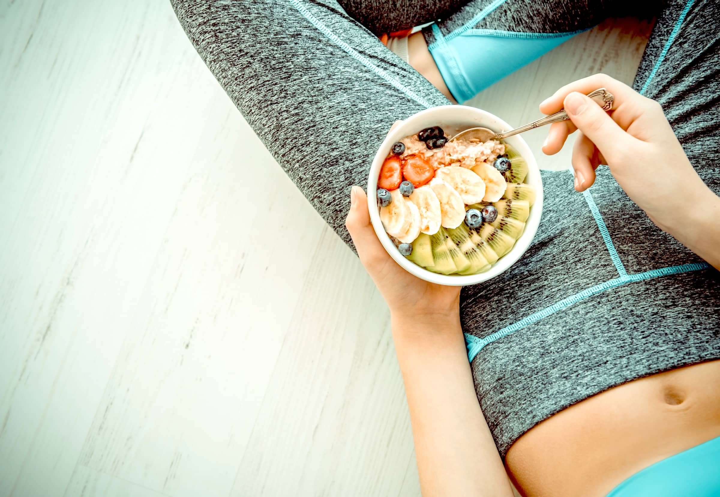 Young woman is resting and eating a healthy oatmeal after a workout