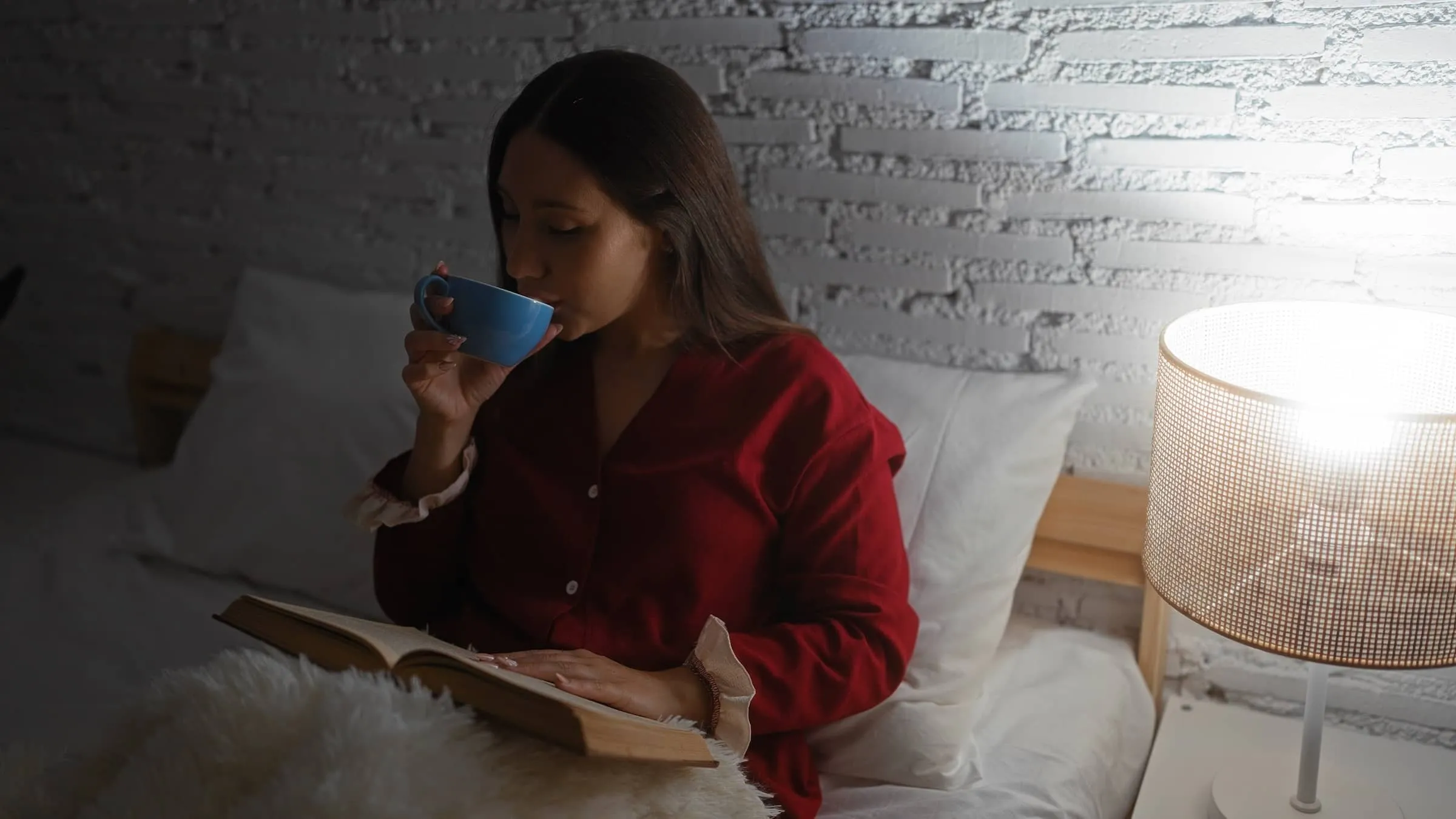 Young brunette woman in red pajamas relaxing on bed