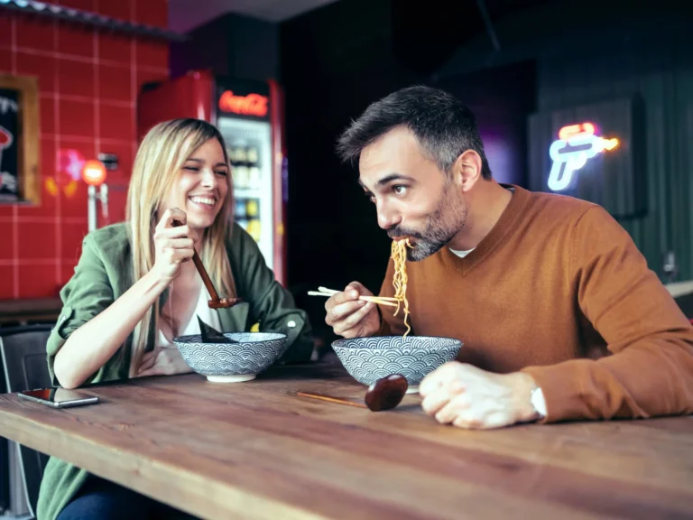 couple eating ramen with chopsticks while having fun in